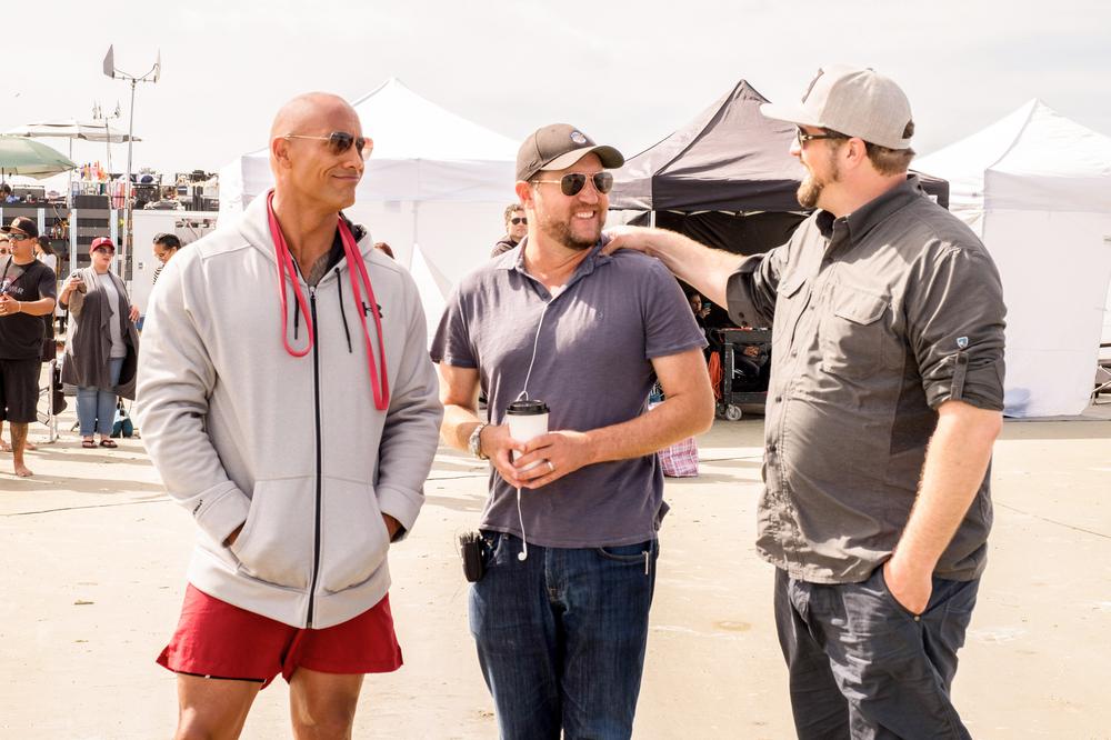BAYWATCH, L-R: DWAYNE 'THE ROCK' JOHNSON, PRODUCER BEAU FLYNN, DIRECTOR SETH GORDON ON SET, 2017. PH: FRANK MASI/©PARAMOUNT PICTURES