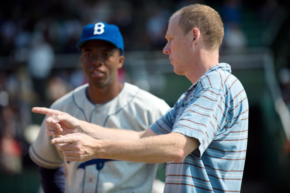 42, (aka FORTY-TWO), from left: Chadwick Boseman as Jackie Robinson, director Brian Helgeland, on set, 2013. ph: D. Stevens/©Warner Bros. Pictures